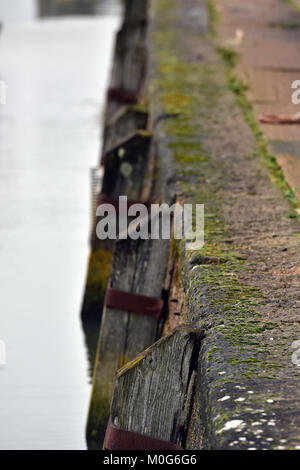 An old unused harbour or dock wall with moss and seaweed growing on the edge. Old ports and docks for shipping no longer used commercially left to rot Stock Photo