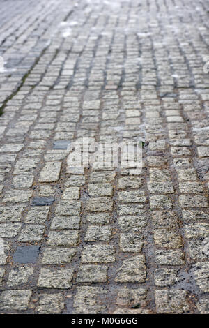 A wet cobbles street in an old and original part of a town. Historic methods of surfacing or building roads. Cobble stones in the rain on a SWT day. Stock Photo