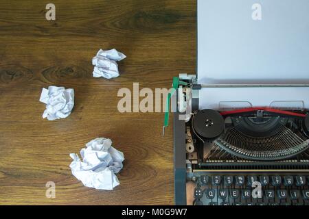 Old typewriter and crumpled paper on wooden desk. Stock Photo