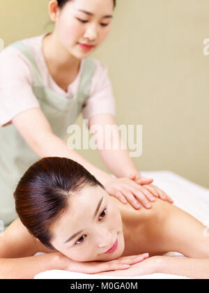 close-up of face of a beautiful young asian woman lying on front on bed receiving massage in spa salon. Stock Photo