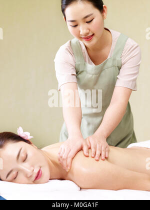 young asian masseur performing massage on woman in spa salon. Stock Photo