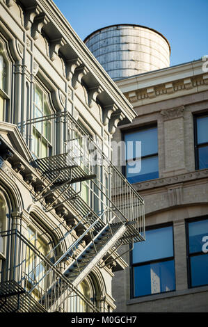 Architectural detail view of traditional fire escape and wooden water tower in the Cast Iron Historic District of SoHo in downtown Manhattan, New York Stock Photo
