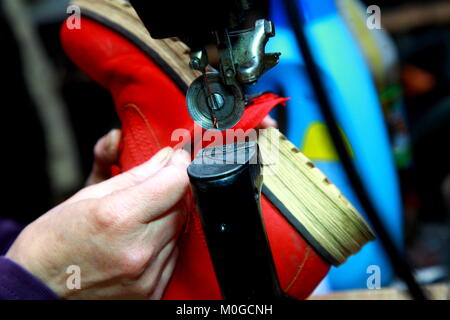 Female hand of a shoemaker sew castle in boots. A sewing needle is shown closeup Stock Photo