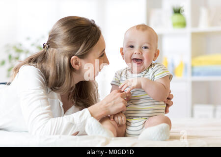 Mom and baby boy playing in sunny bedroom. Happy mother and little child kid relaxing at home. Family having fun together. Stock Photo