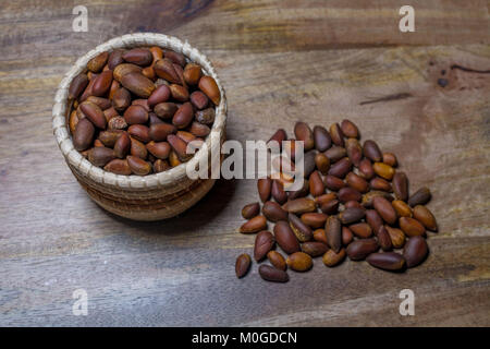 A small basket with pine nuts deorated with pine nuts on aged wooden table Stock Photo