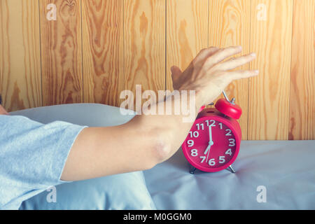 Hand turns off the alarm clock waking up at morning . soft skin tone effect Stock Photo