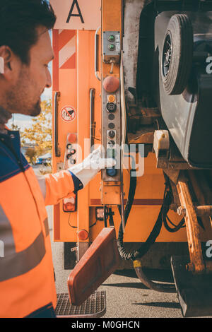 Worker emptying dustbin into waste vehicle Stock Photo