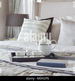 Decorative tray with book and tea set on the bed in modern bedroom Stock Photo