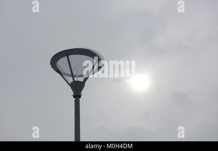 LED street light with grey pole and armature aigainst white winter sky. Stock Photo