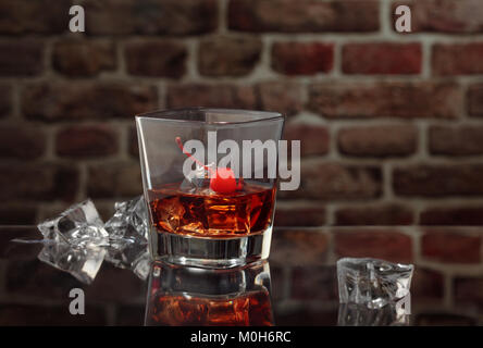 Glass of whiskey with smoking cigar and ice cubes on wooden table. Stock Photo