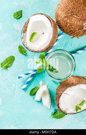 Healthy food concept.  Fresh Organic Coconut Water with coconuts, ice cubes and mint, on light blue background, copy space top view Stock Photo