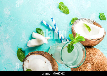 Healthy food concept.  Fresh Organic Coconut Water with coconuts, ice cubes and mint, on light blue background, copy space top view Stock Photo