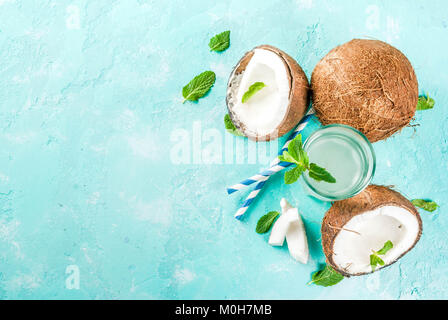 Healthy food concept.  Fresh Organic Coconut Water with coconuts, ice cubes and mint, on light blue background, copy space top view Stock Photo