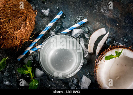 Healthy food concept.  Fresh Organic Coconut Water with coconuts, ice cubes and mint, on rusty dark blue background, copy space top view Stock Photo
