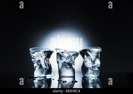 crumpled plastic cups of water on dark  Stock Photo