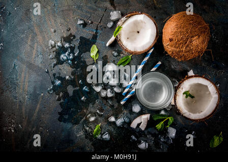 Healthy food concept.  Fresh Organic Coconut Water with coconuts, ice cubes and mint, on rusty dark blue background, copy space top view Stock Photo