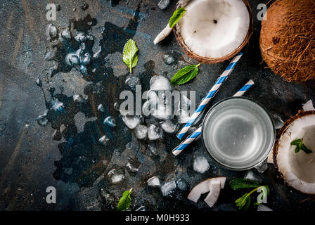 Healthy food concept.  Fresh Organic Coconut Water with coconuts, ice cubes and mint, on rusty dark blue background, copy space top view Stock Photo