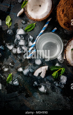 Healthy food concept.  Fresh Organic Coconut Water with coconuts, ice cubes and mint, on rusty dark blue background, copy space top view Stock Photo