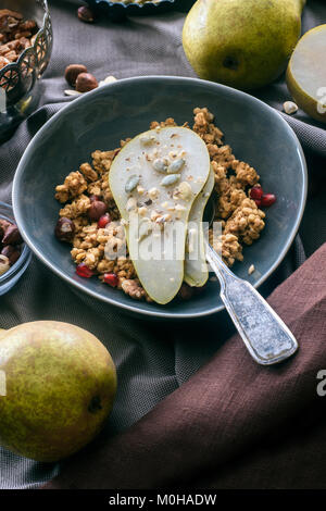 overhead view of granola with pear pieces in bowl Stock Photo