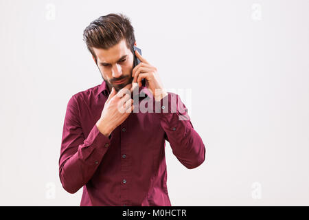 Studio shot portrait of young businessman who is talking on phone. Stock Photo