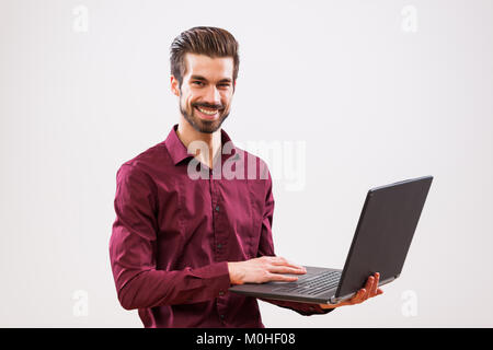 Studio shot portrait of young successful businessman who is using laptop. Stock Photo