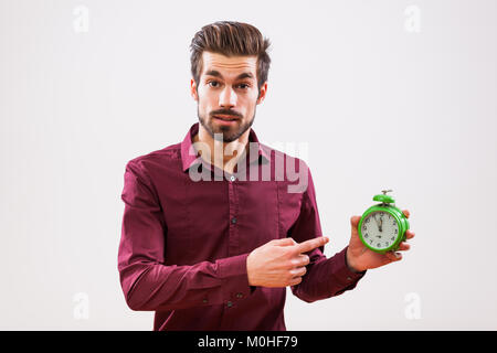 Young businessman is pointing at clock that shows five to twelve time. Stock Photo