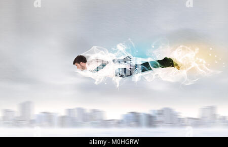 Hero superman flying above city with smoke left behind concept Stock Photo