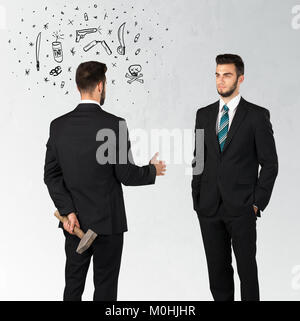 Ruthless businessman handshake with hiding a weapon and weapon symbols around his head Stock Photo