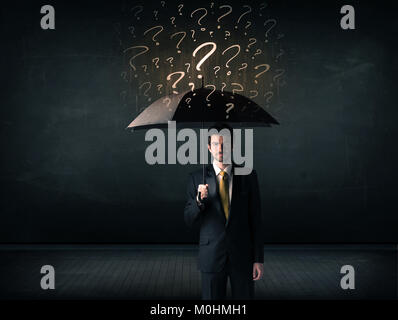 Businessman with umbrella and a lot of drawn question marks concept on background Stock Photo