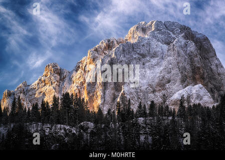 First ray of Sun on the top of mountain Sassolungo in winter morning Stock Photo