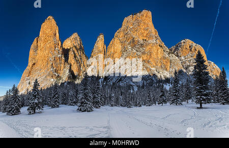 Rays of Sun on the mountains of Gardena Valley in a beautiful winter morning with blue sky in background Stock Photo
