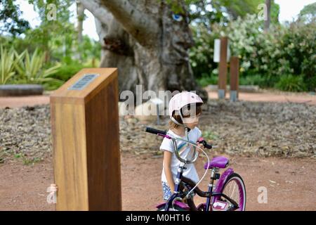 Young girl listening to Billy the bombax tree information, Anderson Park Botanic Gardens, Townsville, Queensland, Australia Stock Photo