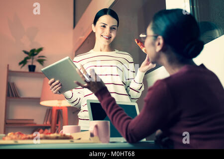 Two women eating pizza and discussing work Stock Photo