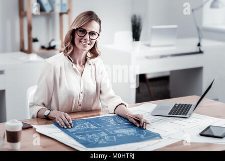 Positive delighted female working at her plan Stock Photo