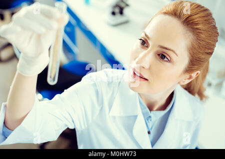 Amazed mature lady analyzing test tube with sample Stock Photo