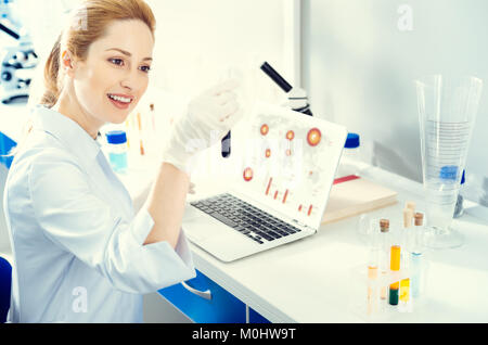 Adult woman analyzing test tube while working in lab Stock Photo