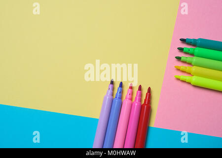 high angle view of some felt pens of different colors on a colorful yellow, pink and blue background, with some blank space on top Stock Photo