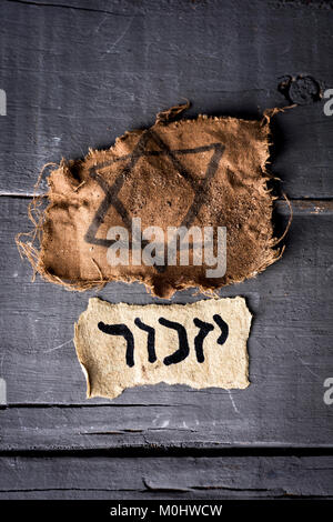 high angle view of a ragged jewish badge and a yellowish piece of paper with the word yizkor, remember in hebrew and the name of a prayer in memory of Stock Photo