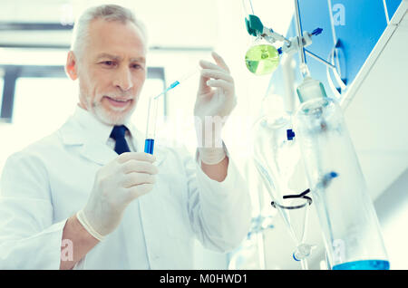 Positive minded scientist mixing chemical liquids in lab Stock Photo