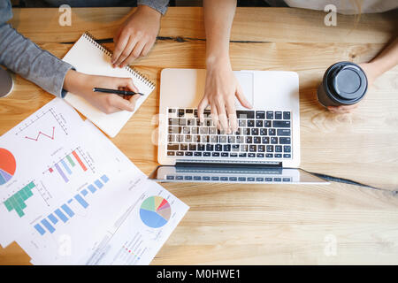 Young women students having a business lunch using laptop making research for project taking notes table top view close-up instagram filter Stock Photo