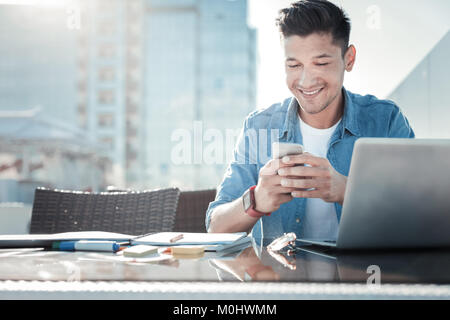 Smiling student using smartphone while doing homework Stock Photo