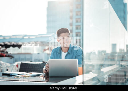 Pensive college guy dreaming while doing home assignment Stock Photo