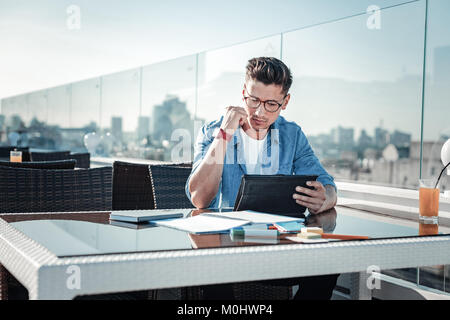 Focused young man working on touchpad in cafe Stock Photo
