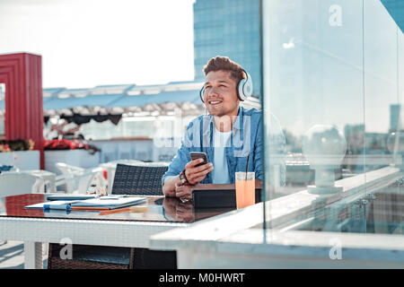 Pensive student enjoying music pleasing in his headphones Stock Photo