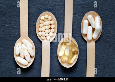 Healthy supplements on wooden spoons against dark slate background Stock Photo