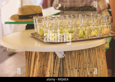 Mohito cocktail glasses with lime pieces, waiting to be filled with drinks on a party table Stock Photo