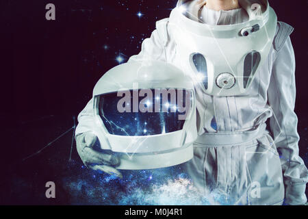 Astronaut in a spacesuit holding a helmet in his hand. Close-up, mixed media Stock Photo