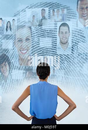 Woman standing hands on hips looking at interface of faces and a fingerprint Stock Photo