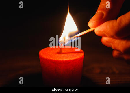 lighting candles in the dark. man's hand lights a candle with a match Stock Photo