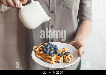 cropped shot of woman pouring maple syrup on tasty waffles Stock Photo